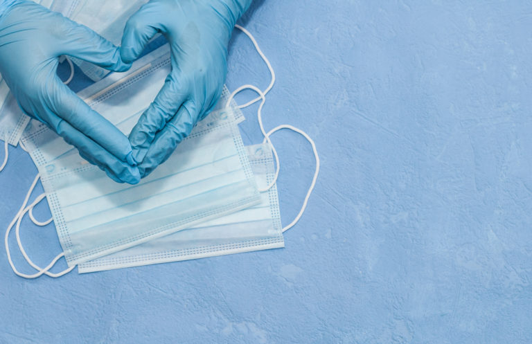 gloved hands making a heart over face masks