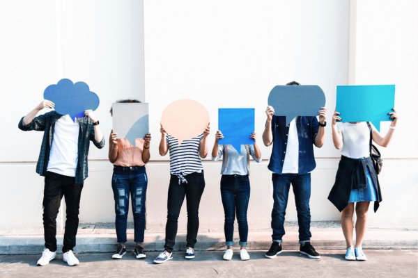 Group of people holding cut outs of speech bubbles over their faces
