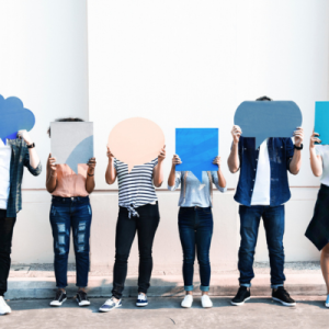 Group of people holding cut outs of speech bubbles over their faces