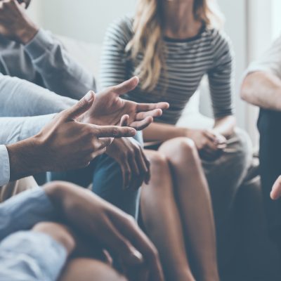 Close-up of people communicating while sitting in circle and gesturing