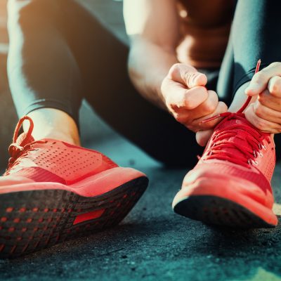 Man tying jogging shoes.He is running outdoors on a sunny day.